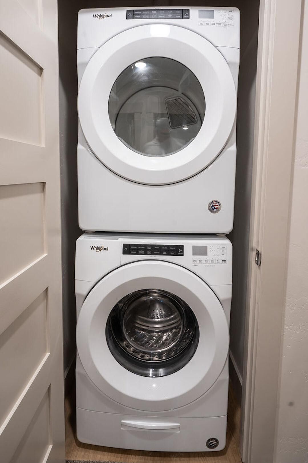 A Whirlpool washer and dryer stacked in a narrow space.