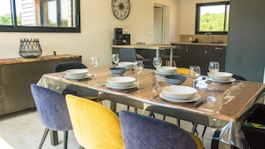 A dining area with a wooden table set for six, surrounded by colorful chairs. - Modern house with great facilities and a large jacuzzi (Crozon)