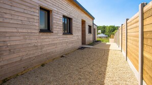 A modern building with horizontal wooden siding and a gravel pathway leading to a door. - Modern house with great facilities and a large jacuzzi (Crozon)