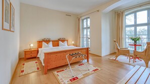 A bedroom with a wooden bed, bedside tables, a chair, a small table with a vase, and large windows. - 2 bedroom amazing apartment in Krakow am See (Krakow am See)