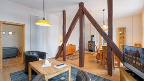 A cozy living room with a wooden staircase, a fireplace, and a television displaying a cityscape. - 2 bedroom amazing apartment in Krakow am See (Krakow am See)