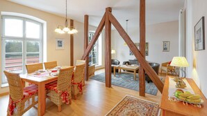 A dining area with a wooden table and chairs, a chandelier, and a view of the outdoors through large windows. - 2 bedroom amazing apartment in Krakow am See (Krakow am See)