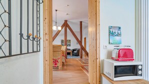 A cozy room with a wooden ceiling, a white microwave on a wooden counter, wicker furniture, and a calendar on the wall. - 2 bedroom amazing apartment in Krakow am See (Krakow am See)