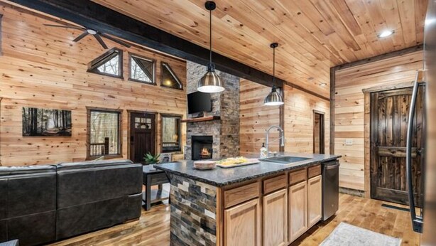 Una cocina moderna con una isla de piedra, paredes de madera y una chimenea.