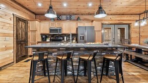 Una cocina moderna con paredes de madera, una isla central con taburetes de bar y electrodomésticos de acero inoxidable.