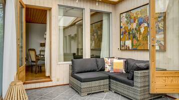 A cozy room with wicker furniture, a painting on the wall, and a door leading to another room.
