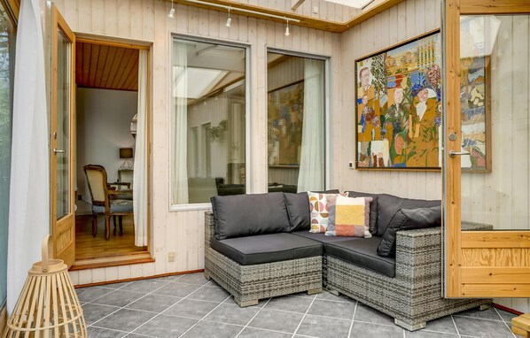 A cozy room with wicker furniture, a painting on the wall, and a door leading to another room.