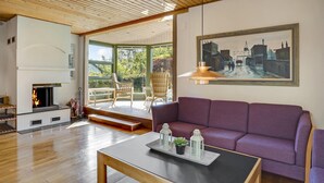 A living room with a fireplace, a purple sofa, and a painting of a cityscape. - Beautiful home in Faxe with kitchen (Faxe)