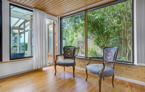 Relax in a spacious room with a high ceiling, large windows, and a comfortable seating area.