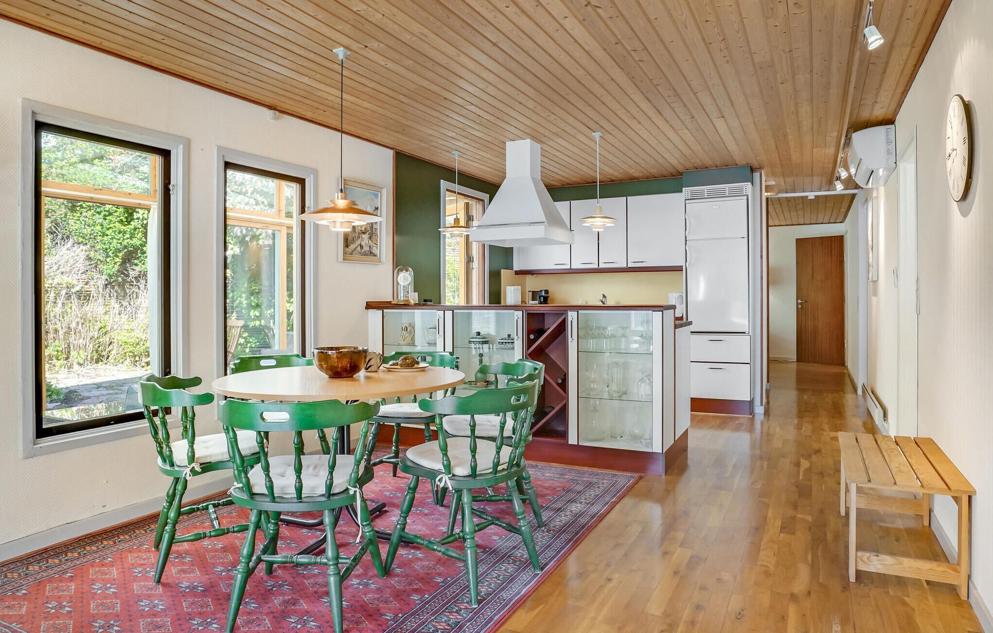 Une cuisine moderne avec des meubles en bois, un îlot central et des chaises vertes.