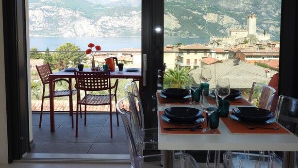A dining area with a table set for two, overlooking a scenic mountain view.