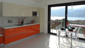 A modern kitchen with a large window overlooking a lake and mountains.