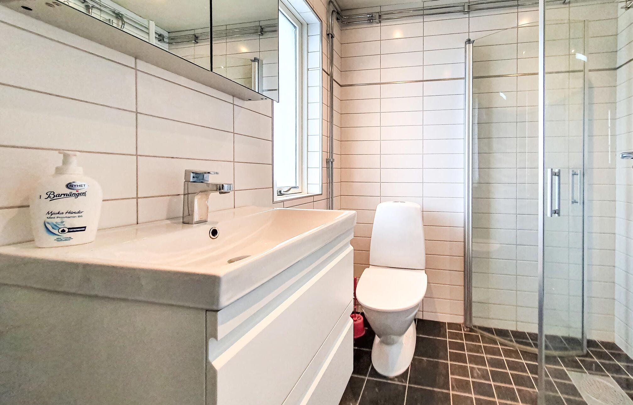 A modern bathroom with a sink, mirror, toilet, and shower.