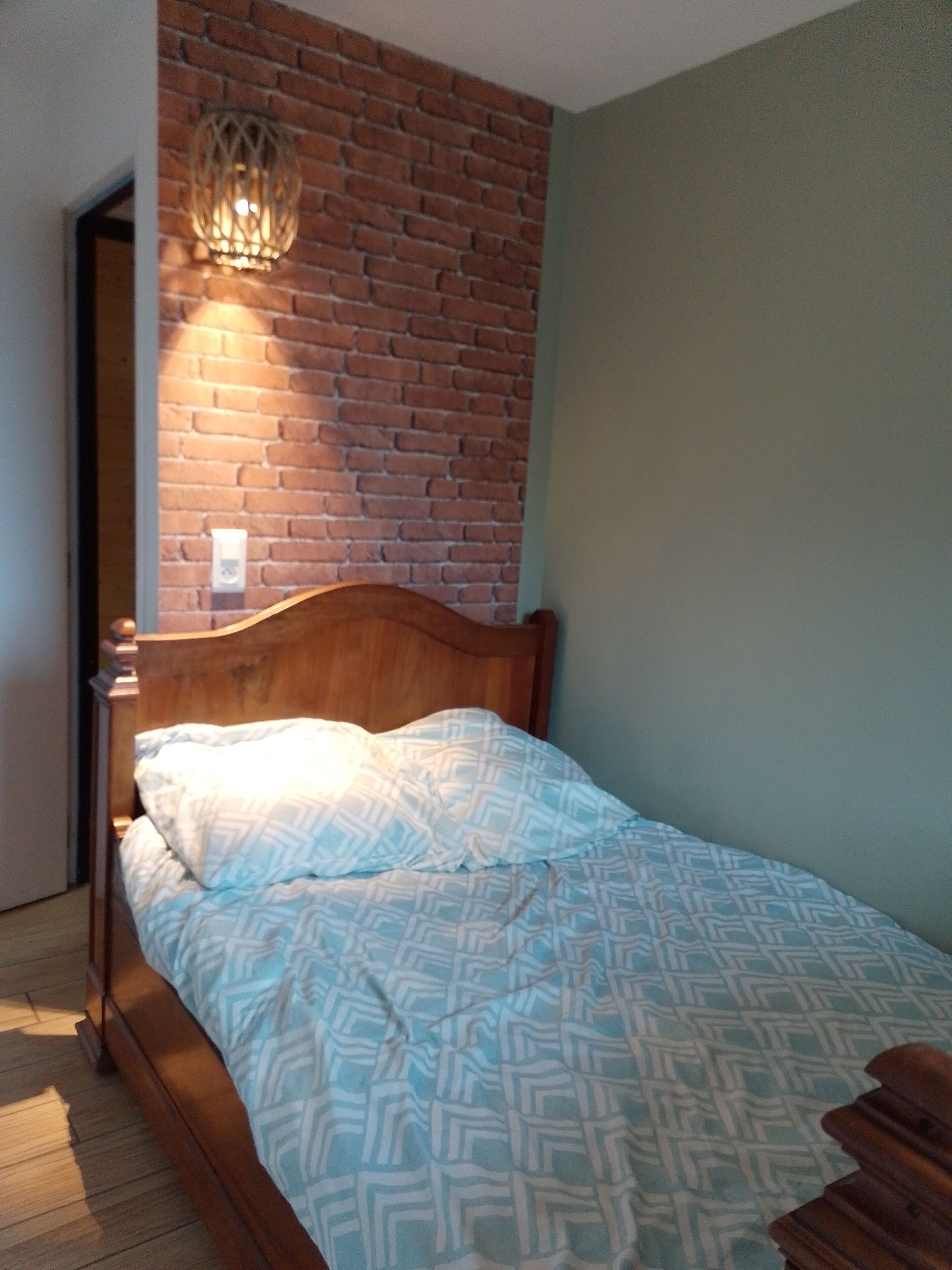 Una camera da letto con un letto di legno, una parete in mattoni e un lampadario.