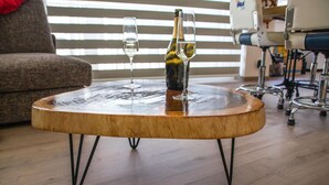 A round wooden coffee table with a bottle and two glasses on top. - Residentie Sint-Paulus (Oostende)