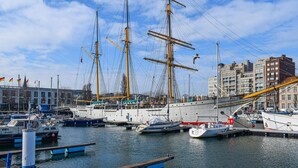 A marina with several sailboats docked, surrounded by buildings and a clear sky. - Residentie Sint-Paulus (Oostende)