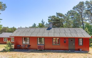 A red building with a corrugated metal roof, a chimney, and a door marked with the number 36.