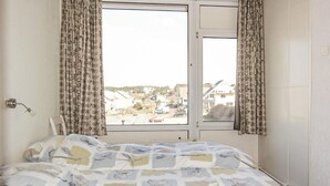 Une chambre à coucher avec un lit, une fenêtre avec des rideaux et une vue sur un quartier résidentiel.