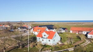 Un village côtier aux maisons traditionnelles, avec un ciel dégagé et une vue sur la mer.