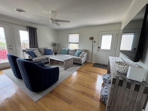 A living room with a sofa, chairs, a coffee table, a TV, and a ceiling fan.