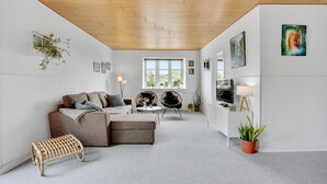 A modern living room with a wooden ceiling, white walls, a sofa, two chairs, a small table, and a TV. - Awesome apartment in Hejls with kitchen (Hejls)