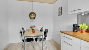 A modern kitchen with a wooden ceiling, a hanging pendant light, a dining table with chairs, and a countertop with a coffee machine and potted plant. - Awesome apartment in Hejls with kitchen (Hejls)