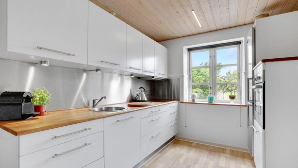 A modern kitchen with white cabinets, a wooden countertop, a stainless steel sink, and a window with a view of greenery. - Awesome apartment in Hejls with kitchen (Hejls)