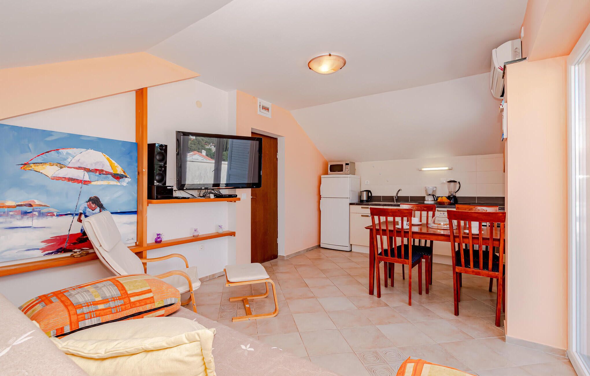 Un espacio habitable compacto con comedor, kitchenette y un cuadro en la pared.