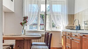 Ett modernt kök med träskåp, ett matbord med stolar och ett fönster med tunna, genomskinliga gardiner.