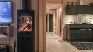 Een modern interieur met een houtkachel, een televisie en een keukenhoek.