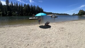 Une plage avec un rivage sablonneux, un parasol bleu et un petit quai muni d’une échelle.