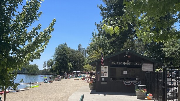 Une plage au bord du lac, avec un petit bâtiment portant l’inscription « Twain Harte Lake ».