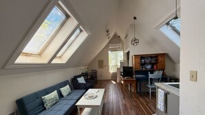 Un appartement de style loft comprenant un coin repas, une kitchenette et une grande fenêtre offrant une vue dégagée.