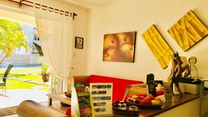 A reception area with a red sofa, a wooden reception desk, a small statue, and a view of the outdoor garden. - 19 Pax Family double Pool Villa (Playa del Carmen)