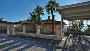 Ein Wohnhaus mit geschlossenem Eingangstor, einer Veranda und Blick auf das Meer.