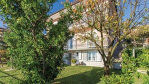 Ein Wohngebäude mit gepflegtem Garten, einem sichtbaren Balkon und blauem Himmel.