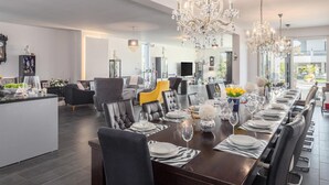 Ein geräumiger Essbereich mit einem langen Tisch, gedeckt für eine Mahlzeit, umgeben von modernen Stühlen und eleganten Kronleuchtern.