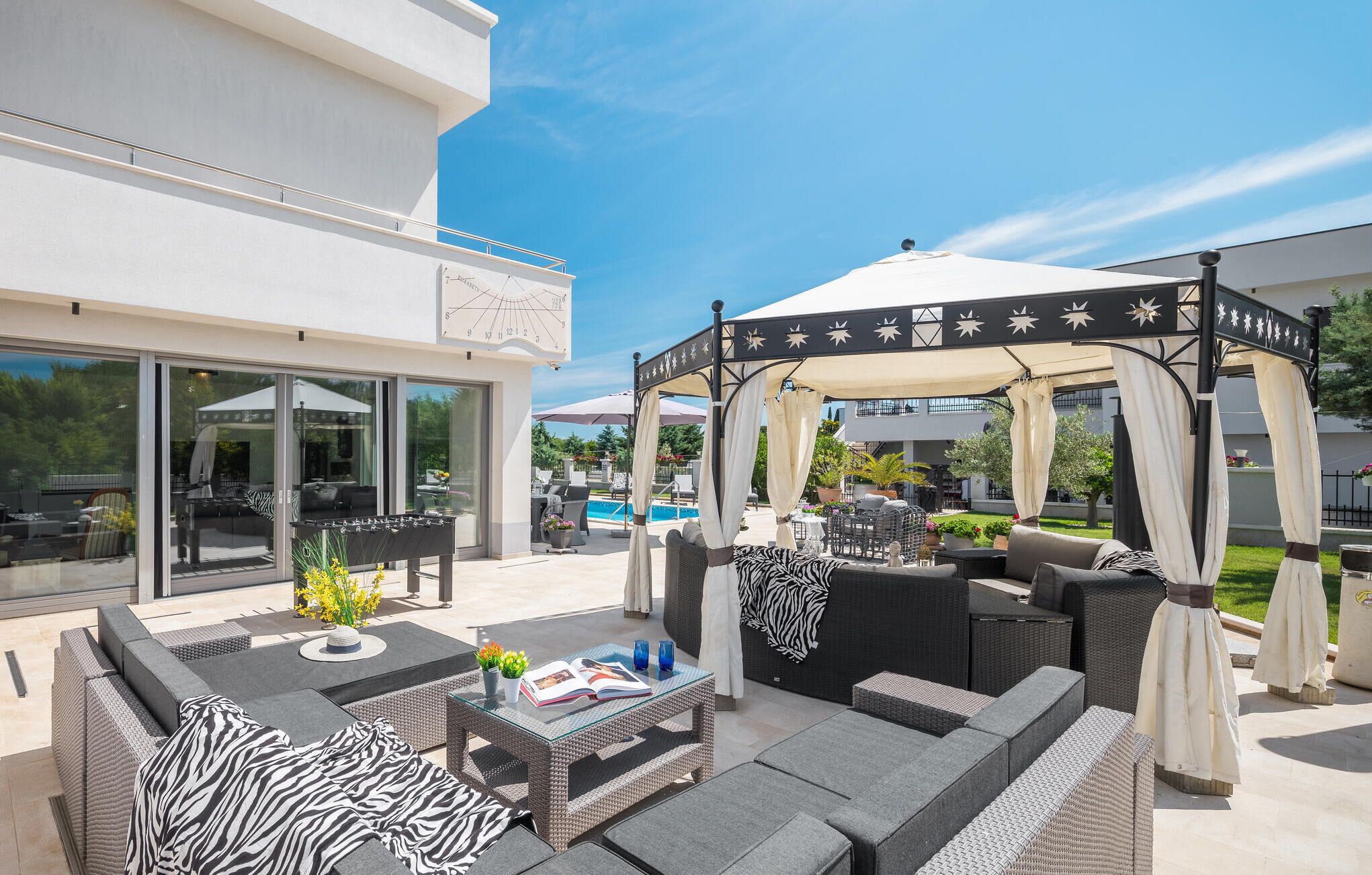 An outdoor patio with wicker furniture, a glass table, and a covered seating area.