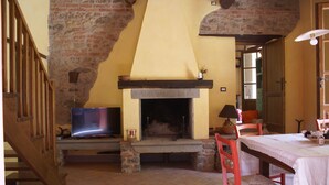 A cozy living room with a fireplace, wooden staircase, and a dining area with a table and chairs. - Tuscan tradition renovated in 2021 (Barga)