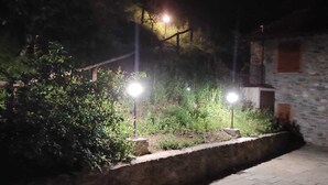 A nighttime outdoor area with stone walls, a paved walkway, and two illuminated street lamps. - Tuscan tradition renovated in 2021 (Barga)