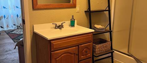 Un baño con tocador de madera, un espejo, un estante y un inodoro.