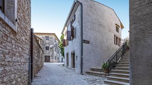 Una stretta strada acciottolata affiancata da edifici storici in pietra, con una scala che conduce a un secondo piano.
