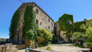 A stone building with ivy-covered walls and a courtyard with outdoor seating. - Gorgeous apartment in CARCHETO BRUSTICO (CARCHETO BRUSTICO)