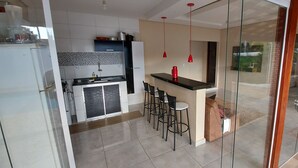Une cuisine moderne avec un coin repas, une cloison en verre et une vue sur l’extérieur.