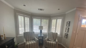 A corner room with two armchairs, a table with a lamp, and a patterned rug. - Redding Country Cottage (Redding)