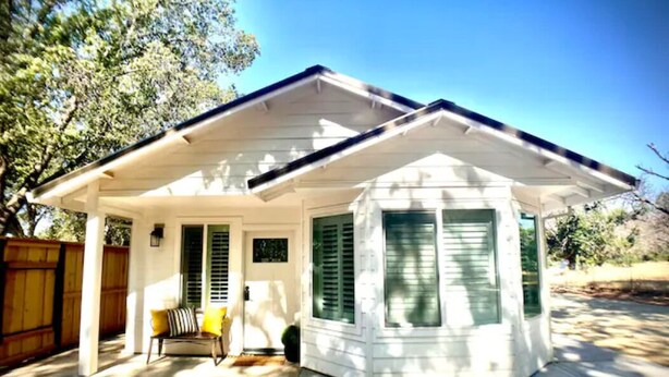 A single-story house with a covered porch, a small front yard, and a wooden fence. - Redding Country Cottage (Redding)