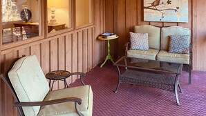 A cozy room with wooden paneling, a sofa set, a small table, and a painting of birds on a branch. - Cozy Cabin with fireplace and screened in porch in Sapphire Valley. (Sapphire)