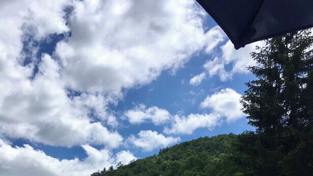 A swimming pool with two people in the water, surrounded by lounge chairs and umbrellas. - Cozy Cabin with fireplace and screened in porch in Sapphire Valley. (Sapphire)