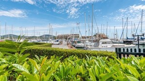 Una marina con varios barcos amarrados, rodeada de vegetación y edificios al fondo.