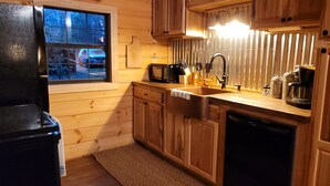 A wooden-paneled kitchen with a window, a microwave, a sink, and a dishwasher. - Secluded East TN Log Cabin (Ten Mile)